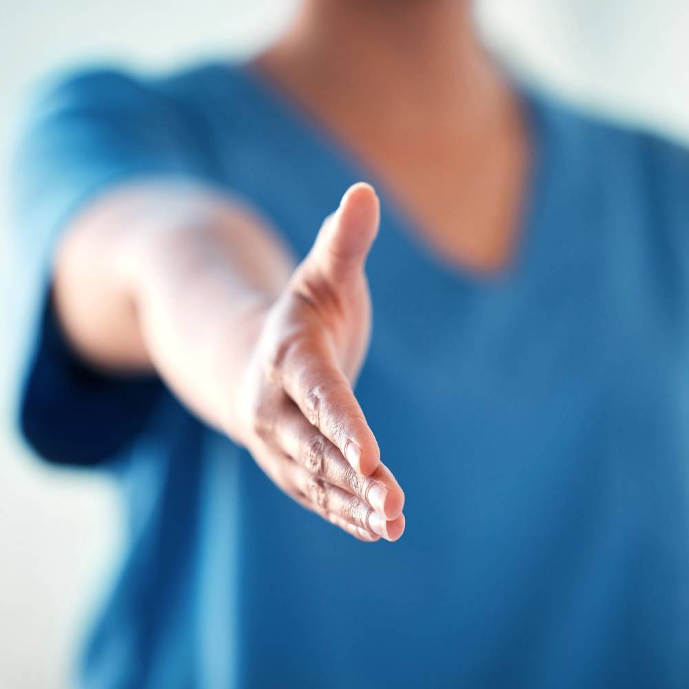 A blurred image of a woman wearing Onna by Premier scrub tunic in ceil blue with hand outstretched