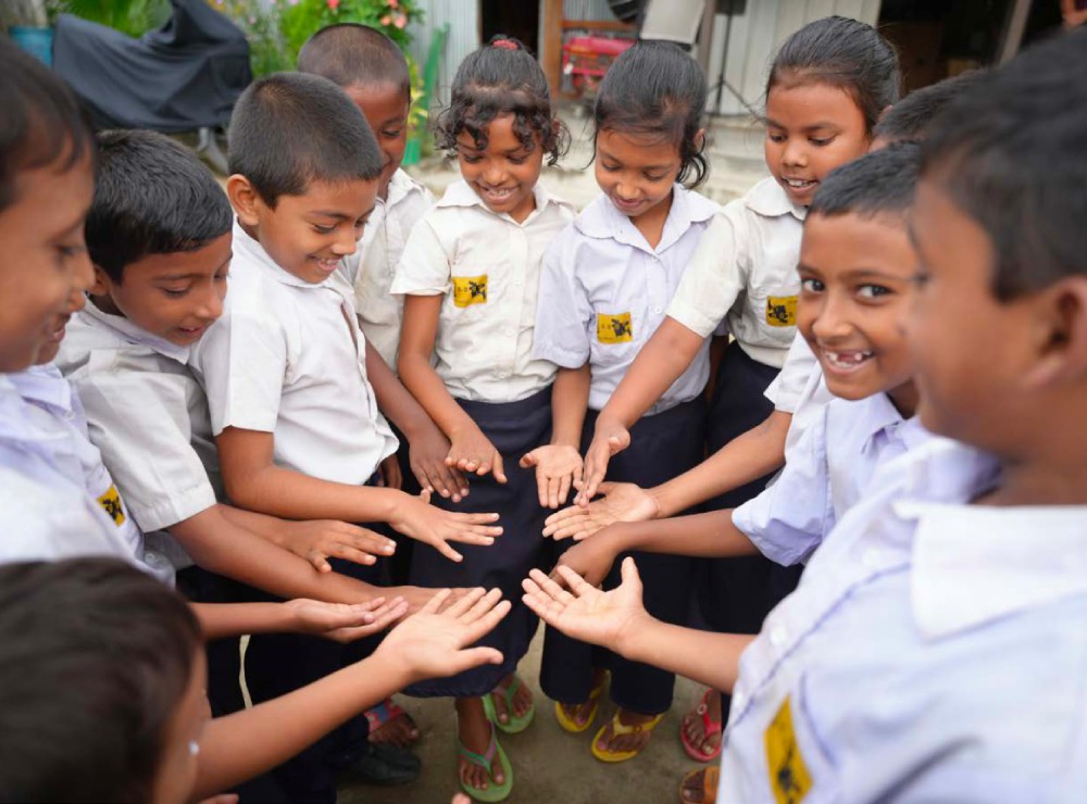 Children standing in a circle looking at the palms of their hands